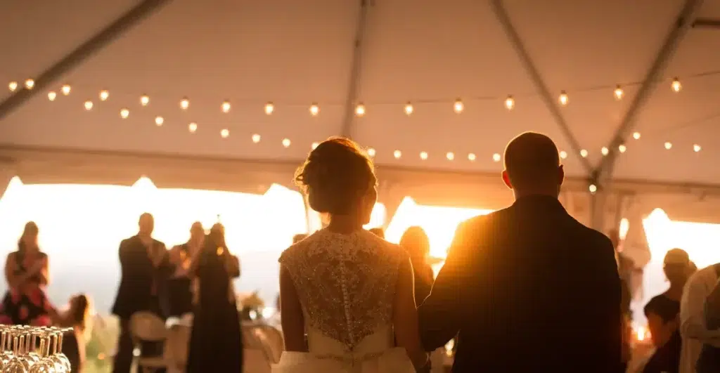 Couple marrying under a tent with string lighting, a perfect example of tent rental costs for weddings